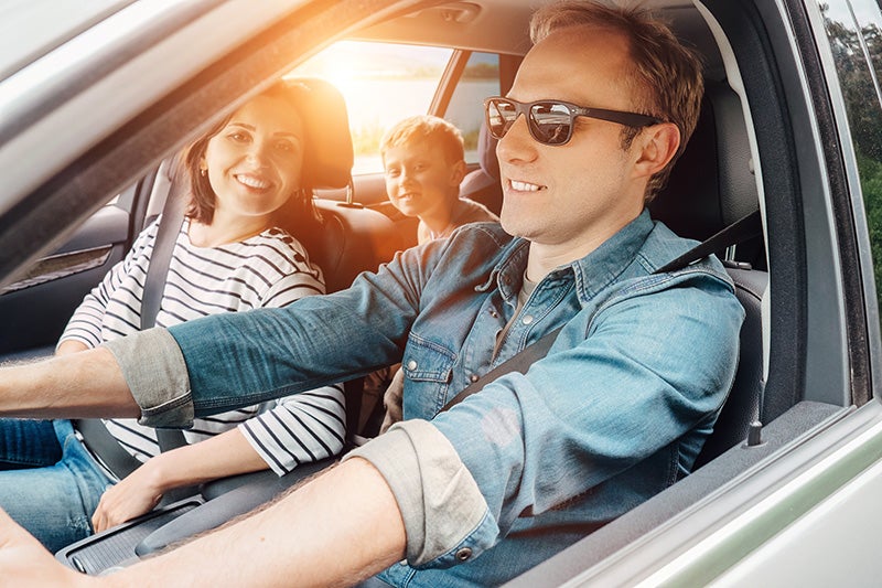 A man, woman and child driving in a car